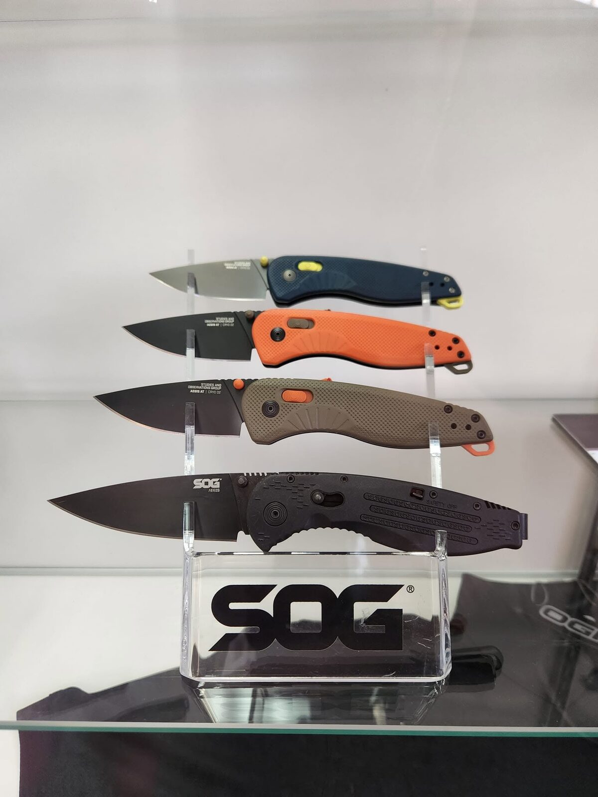 Four SOG Aegis folding knives on a display stand