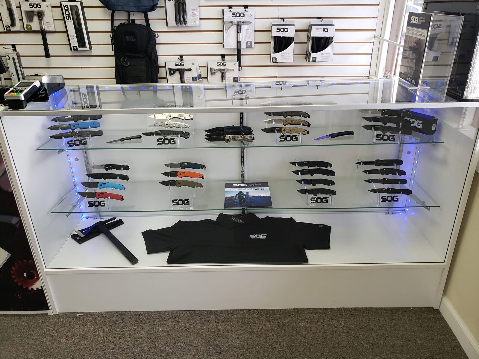 A lit glass display case full of SOG folding knives