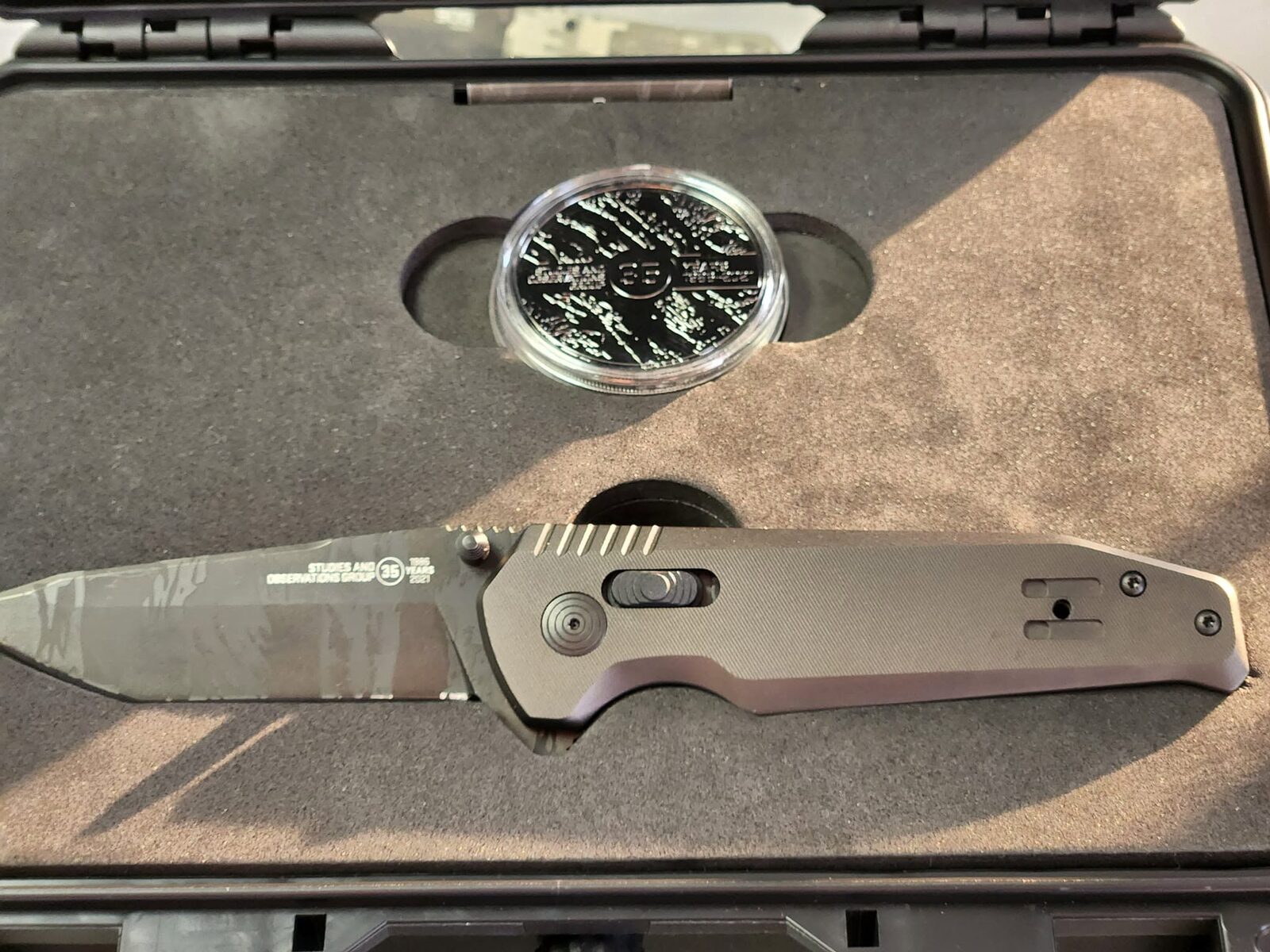 A collector SOG folder with a tiger-stripe camo blade in a case