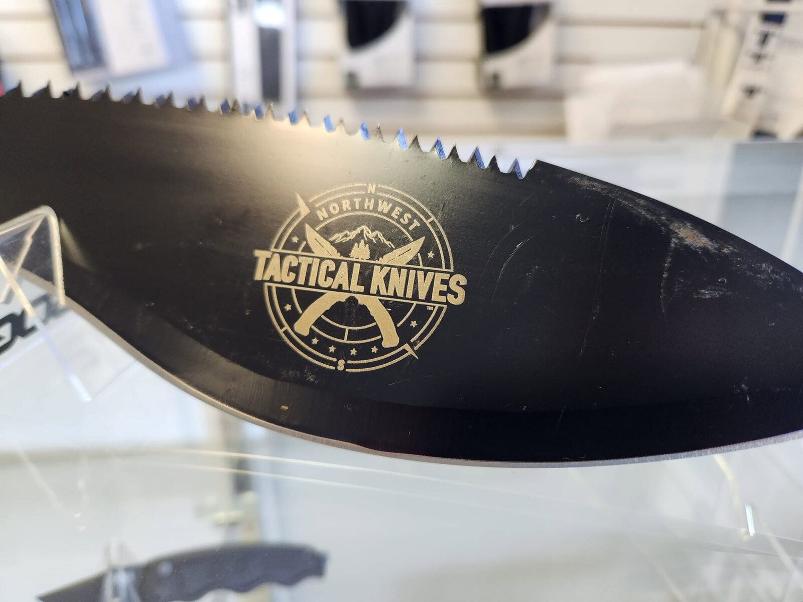 A black tactical blade laser-etched with the NorthWest Tactical Knives compass logo in gold